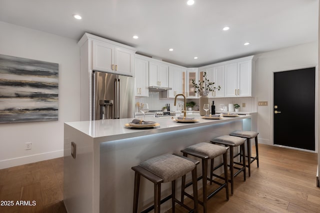 kitchen with white cabinetry, baseboards, decorative backsplash, and high quality fridge
