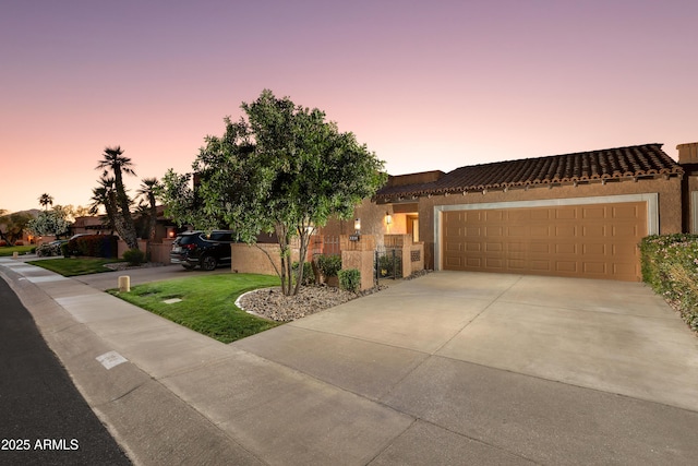 view of front of home with an attached garage, stucco siding, driveway, and a tile roof
