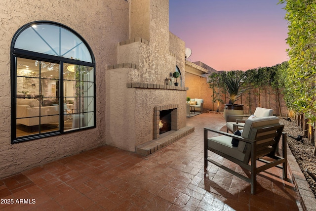 patio terrace at dusk with fence and a lit fireplace