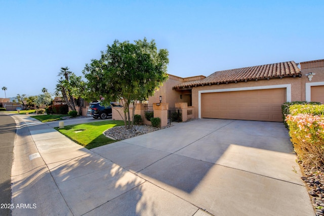 mediterranean / spanish home with a tiled roof, fence, concrete driveway, an attached garage, and stucco siding