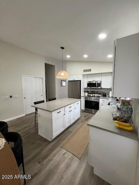 kitchen with hanging light fixtures, stainless steel appliances, dark hardwood / wood-style floors, white cabinets, and a kitchen island