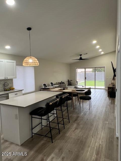 kitchen featuring white cabinetry, decorative light fixtures, dark hardwood / wood-style floors, and a kitchen bar