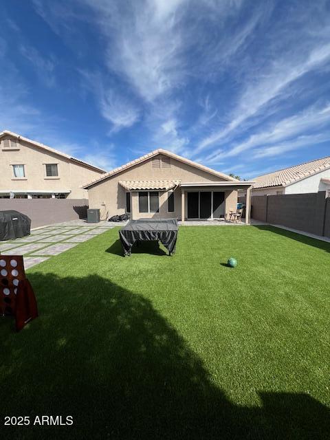 back of house featuring a lawn and a patio area