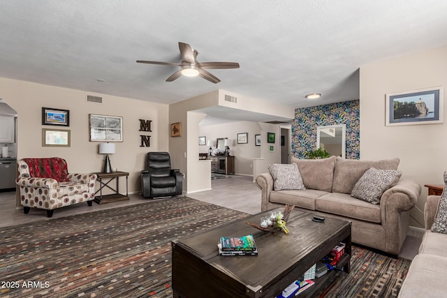 carpeted living room featuring baseboards, visible vents, and ceiling fan