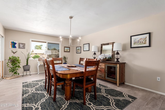dining room with an inviting chandelier, light wood-style flooring, and baseboards