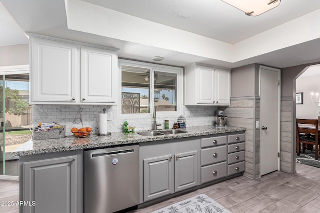 kitchen with light stone countertops, a sink, gray cabinetry, dishwasher, and white cabinets