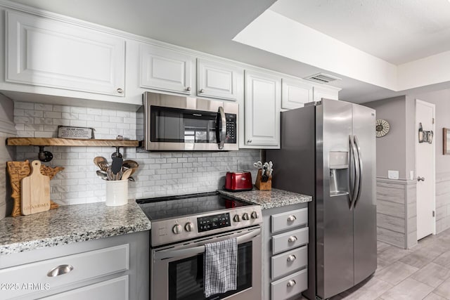 kitchen featuring light stone counters, appliances with stainless steel finishes, white cabinets, light wood finished floors, and visible vents