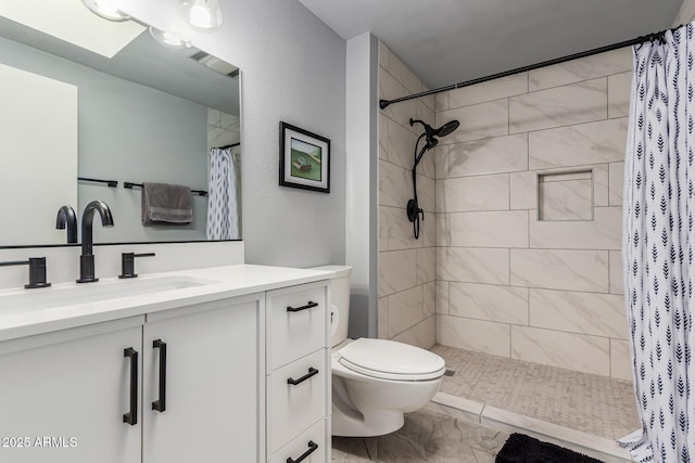 full bathroom with toilet, a tile shower, vanity, and marble finish floor