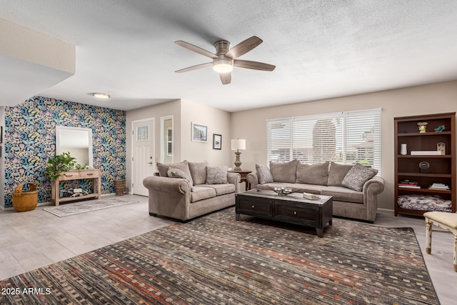 living room with wood finished floors, wallpapered walls, ceiling fan, baseboards, and a textured ceiling