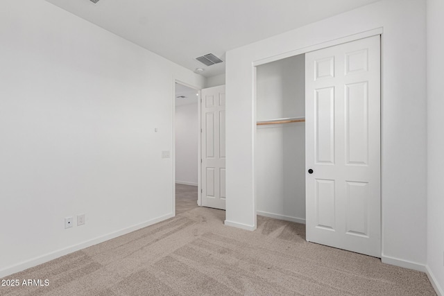 unfurnished bedroom with light colored carpet and a closet