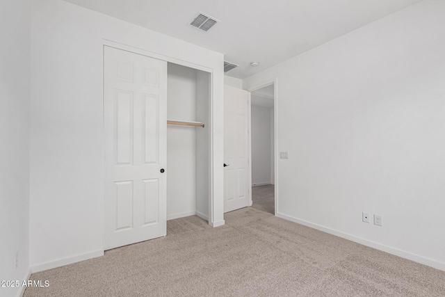 unfurnished bedroom featuring light carpet and a closet