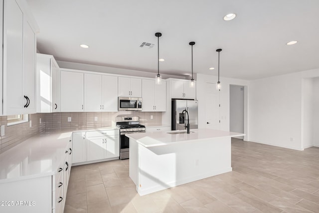 kitchen featuring pendant lighting, a kitchen island, white cabinets, and appliances with stainless steel finishes