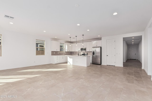 kitchen featuring sink, stainless steel appliances, an island with sink, white cabinets, and decorative light fixtures