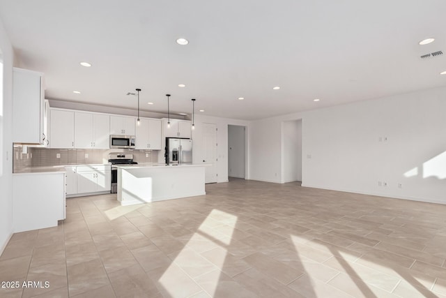 kitchen with white cabinetry, a center island, hanging light fixtures, stainless steel appliances, and decorative backsplash