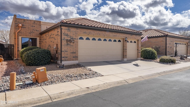 view of front of house featuring concrete driveway, a tile roof, brick siding, and an attached garage