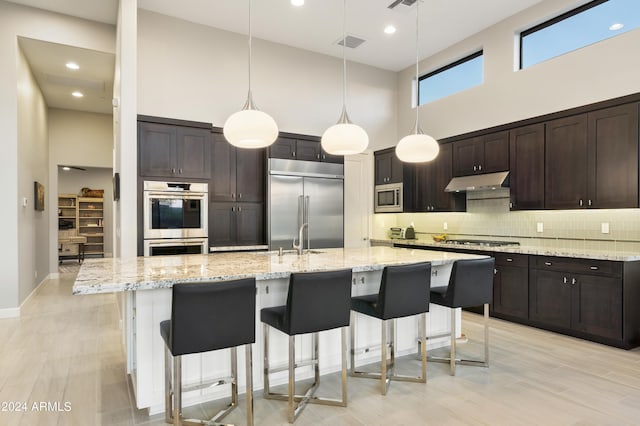 kitchen with built in appliances, dark brown cabinetry, pendant lighting, and a high ceiling