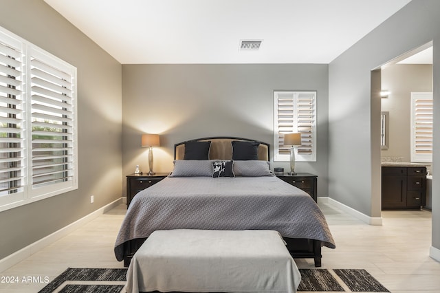 bedroom with ensuite bath and light hardwood / wood-style floors