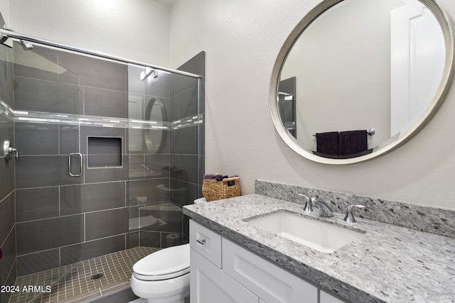 bathroom with vanity, toilet, and a shower with door