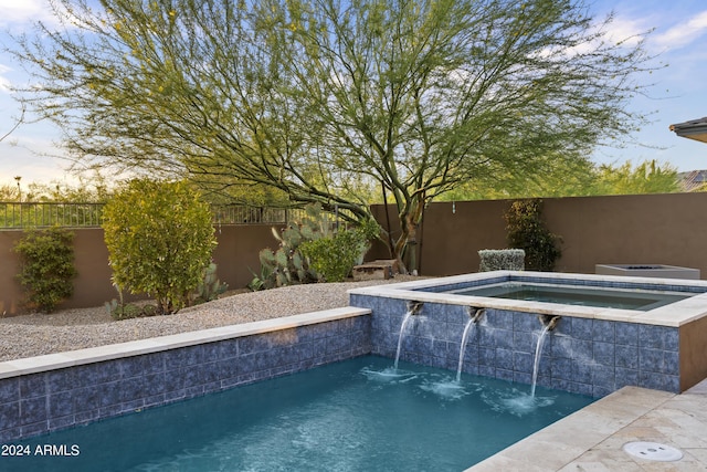 pool at dusk with an in ground hot tub and pool water feature