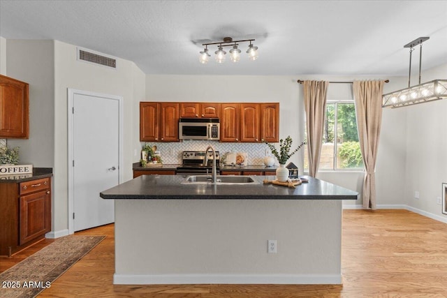 3784 E Washington Ct, Gilbert, AZ 85234 - kitchen with appliances with stainless steel finishes, a sink, dark countertops, light wood-style flooring, and decorative backsplash