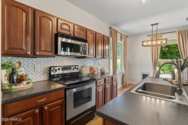 3784 E Washington Ct, Gilbert, AZ 85234 - kitchen featuring stainless steel appliances, a sink, dark countertops, tasteful backsplash, and pendant lighting
