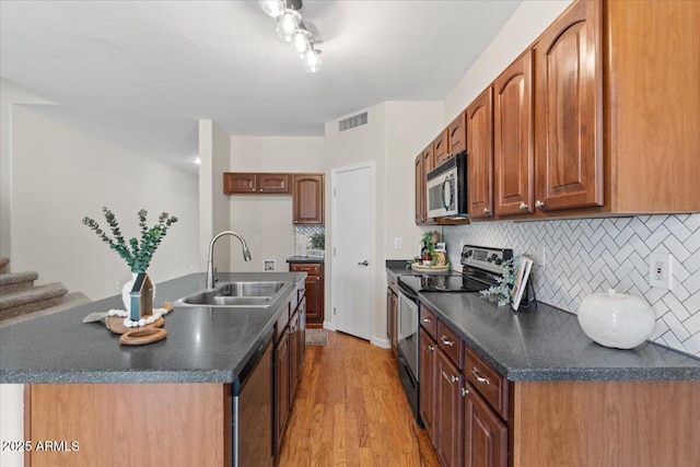 3784 E Washington Ct, Gilbert, AZ 85234 - kitchen with appliances with stainless steel finishes, a sink, dark countertops, light wood-style flooring, and backsplash
