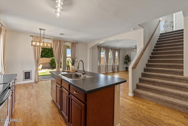 3784 E Washington Ct, Gilbert, AZ 85234 - kitchen featuring a sink, dark countertops, light wood-style floors, baseboards, and arched walkways