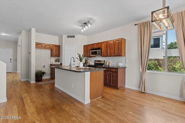 3784 E Washington Ct, Gilbert, AZ 85234 - kitchen with appliances with stainless steel finishes, dark countertops, decorative backsplash, and light wood-style floors