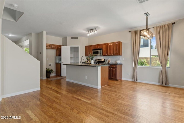 3784 E Washington Ct, Gilbert, AZ 85234 - kitchen with dark countertops, backsplash, stainless steel appliances, light wood-style floors, and brown cabinetry