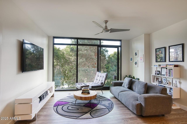 living area featuring a wall of windows, a ceiling fan, and wood finished floors