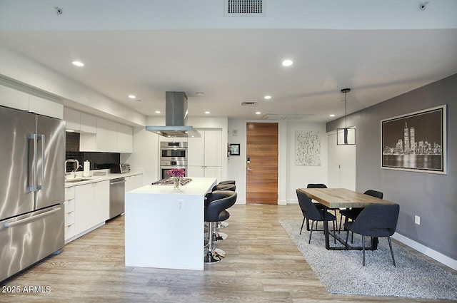 kitchen featuring a center island, decorative light fixtures, light countertops, appliances with stainless steel finishes, and white cabinets