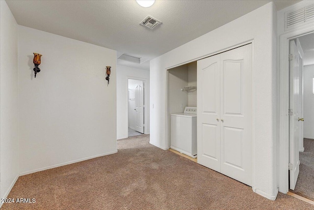 unfurnished bedroom with washer / dryer, light carpet, and a closet