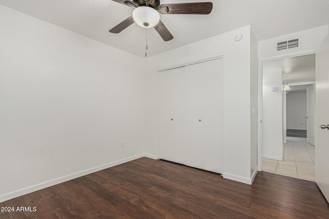 unfurnished bedroom featuring dark wood-type flooring, ceiling fan, a closet, and a textured ceiling