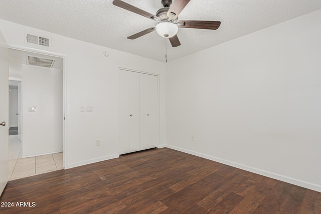 unfurnished bedroom with a closet, a textured ceiling, dark hardwood / wood-style floors, and ceiling fan