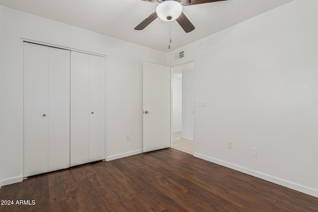 unfurnished bedroom with dark wood-type flooring, ceiling fan, a closet, and a textured ceiling