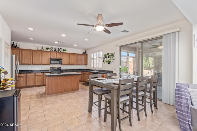 kitchen featuring light tile patterned floors, a center island, ceiling fan, and black appliances