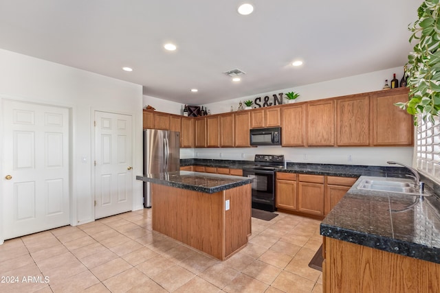 kitchen featuring sink, a kitchen island, dark stone countertops, light tile patterned flooring, and black appliances