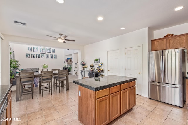 kitchen featuring stainless steel fridge, a center island, light tile patterned floors, and ceiling fan