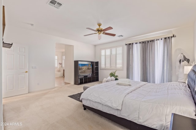 carpeted bedroom with ensuite bath and ceiling fan