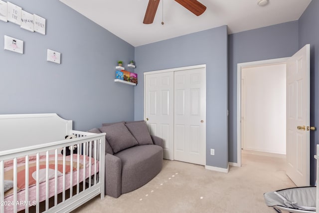 carpeted bedroom featuring a closet, a nursery area, and ceiling fan