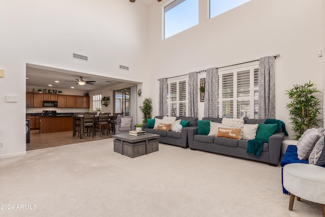 living room with light carpet, a towering ceiling, and a wealth of natural light