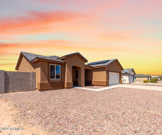 10785 W Arivaca Dr, Arizona City, AZ 85123 - ranch-style home with roof mounted solar panels, a garage, stucco siding, fence, and driveway
