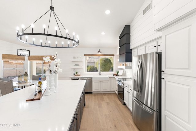 kitchen with sink, stainless steel appliances, white cabinets, and premium range hood