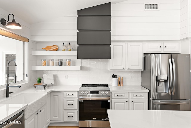 kitchen with lofted ceiling, sink, stainless steel appliances, light stone countertops, and white cabinets