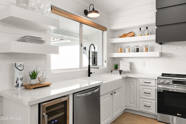 kitchen with sink, appliances with stainless steel finishes, white cabinetry, wine cooler, and tasteful backsplash