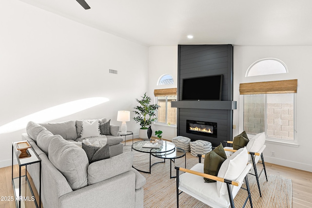 living room featuring lofted ceiling, light hardwood / wood-style floors, and a large fireplace