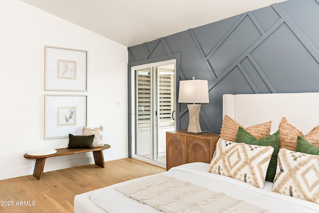 bedroom featuring light hardwood / wood-style flooring, access to exterior, and vaulted ceiling