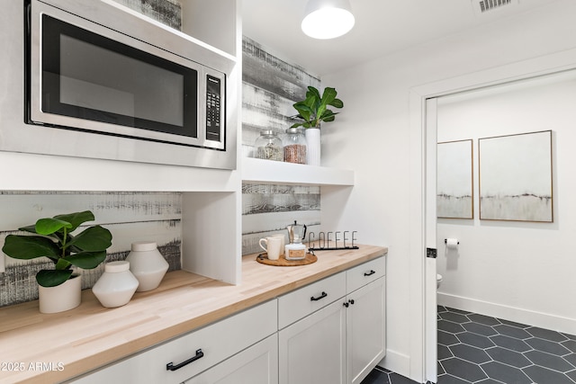 bar with white cabinets, stainless steel microwave, and wooden counters