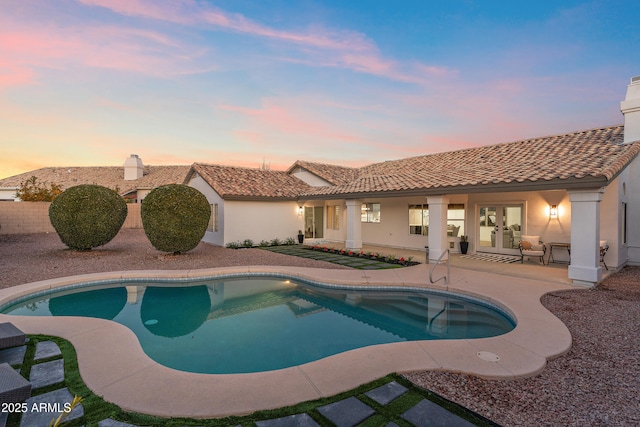 pool at dusk with a patio area