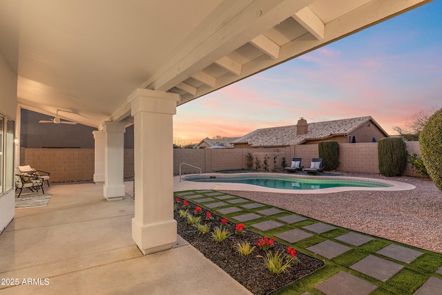 pool at dusk featuring a patio and ceiling fan